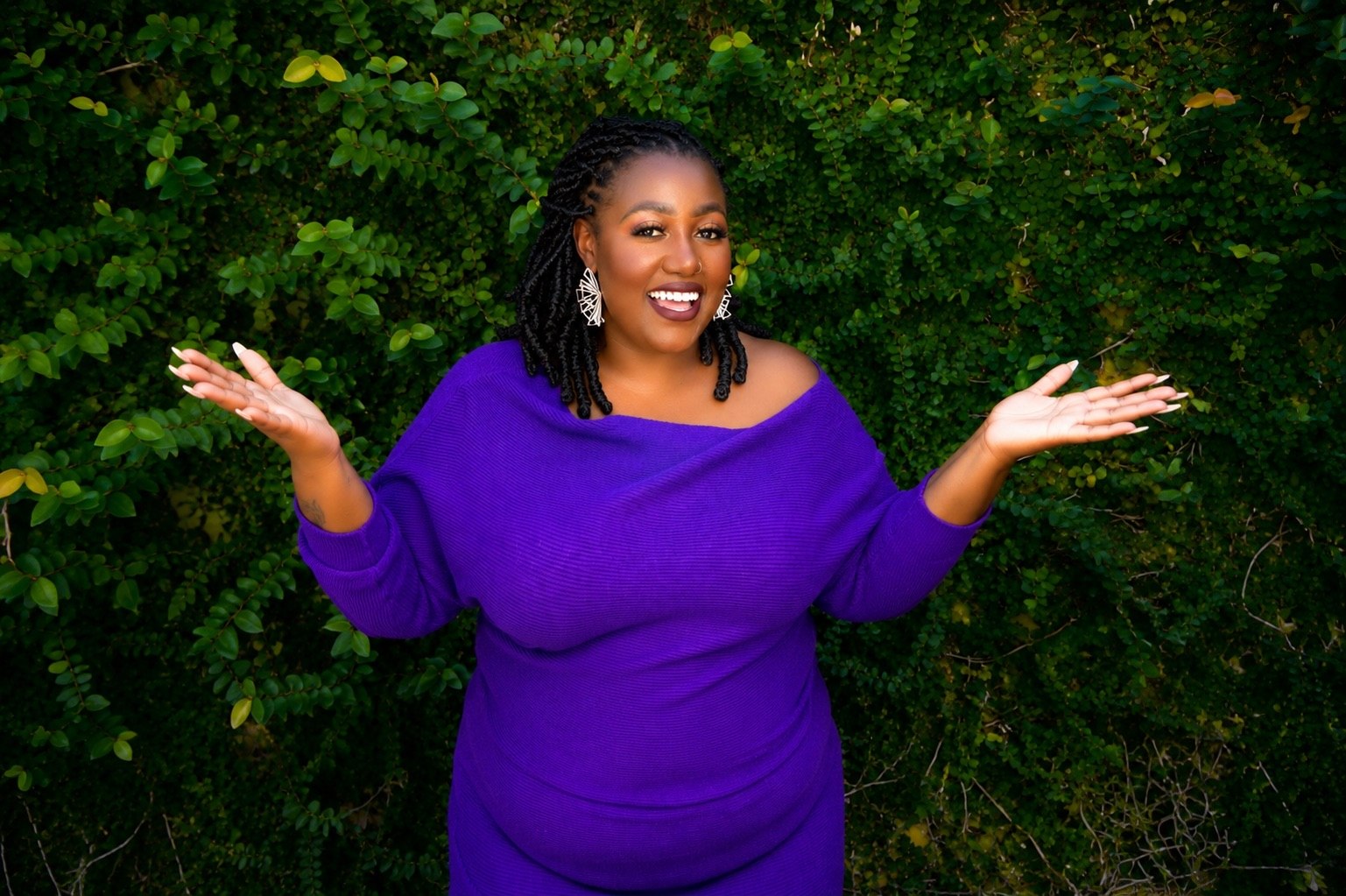 Marliceia Chavers, founder of The Audit Ally, smiling with open arms in a purple dress